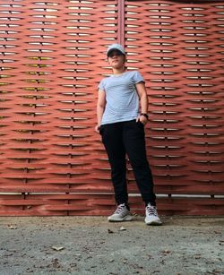 Full length portrait of a woman standing against steel wall