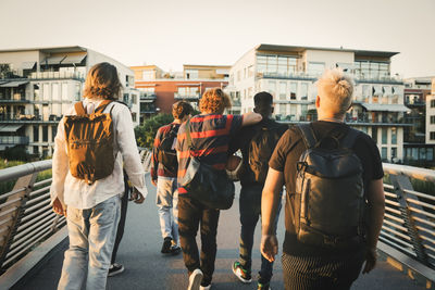 Young and teenage male friends walking on bridge in city