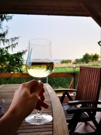 Midsection of man holding beer glass against sky