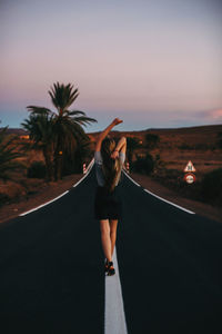 Rear view of woman standing on road against sky