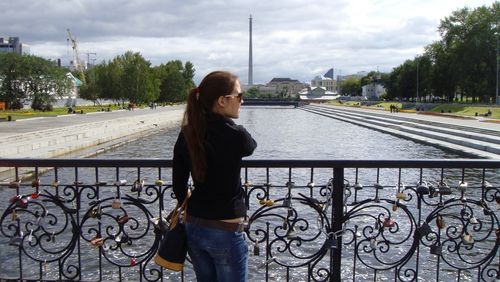 Rear view of woman standing on bridge over canal against yekaterinburg tv tower
