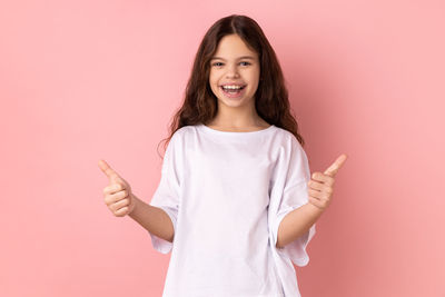 Portrait of young woman holding gift against pink background