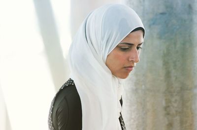 Close-up side view of young woman standing against black background