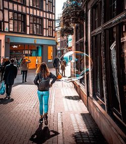 Rear view of people walking on street in city