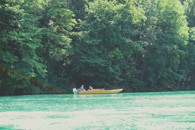 People in boat on river against trees in forest