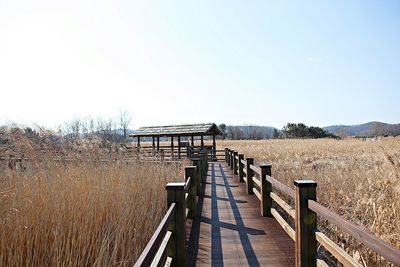 Footbridge on field against clear sky