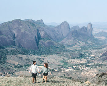 Rear view of man walking on mountain against sky