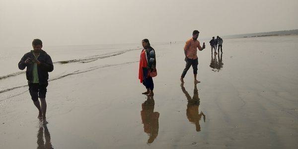 People walking on beach against sky