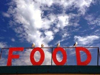 Low angle view of road sign against cloudy sky