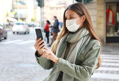 Woman using phone while standing on street