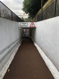 Road sign on footpath by wall