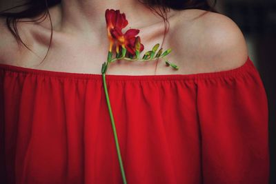 Midsection of woman wearing red off shoulder with flowers