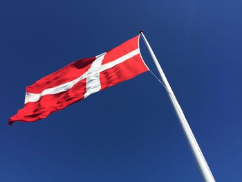 Low angle view of danish flag against clear blue sky