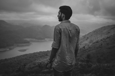 Rear view of man looking at mountains against sky