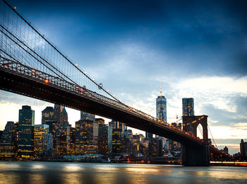 Low angle view of brooklyn bridge over river against sky during sunset