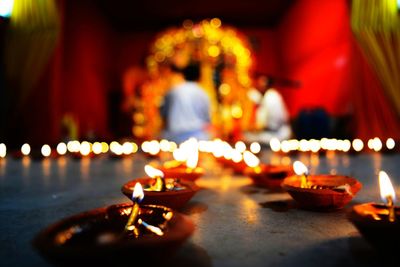 Close-up of lit diyas in temple