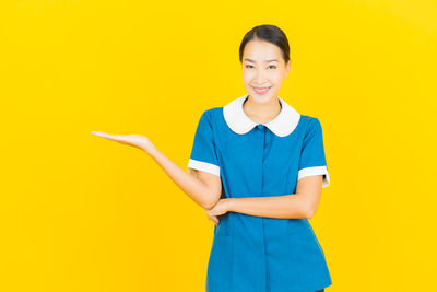 Portrait of a smiling young woman against yellow background