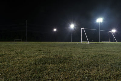 Empty soccer field against sky at night