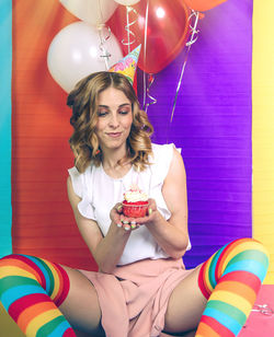 Portrait of smiling young woman holding colorful balloons