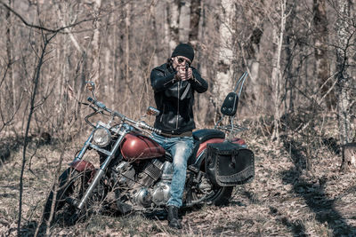 Full length of mid adult man sitting on motorcycle in forest