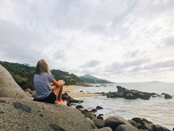 Woman sitting alone looking over snot beach