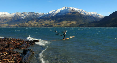 Scenic view of sea and snowcapped mountains against clear sky