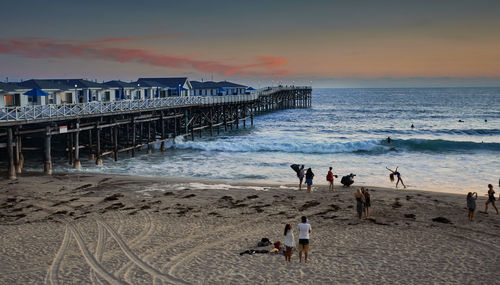 People at beach against sky during sunset