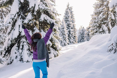 Rear view of woman standing on snow covered field