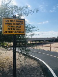 Information sign by road against sky during winter