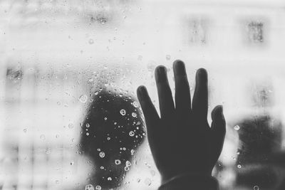 Cropped hand of person touching wet glass