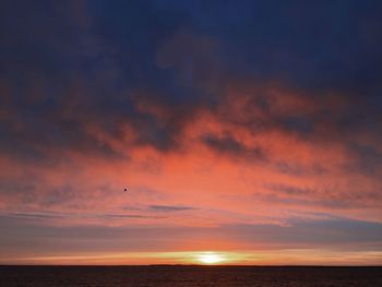 Scenic view of sea against dramatic sky during sunset