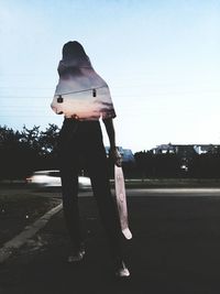 Rear view of woman standing on road against clear sky