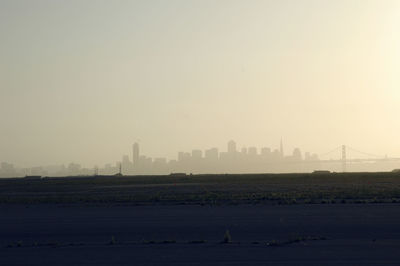 Scenic view of field against cityscape and sky