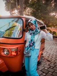 Portrait of smiling woman standing by car