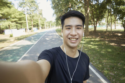 Portrait of smiling young man against trees