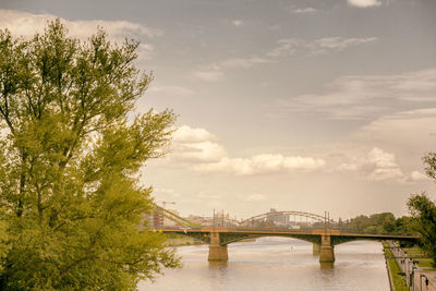 Bridge over river against cloudy sky