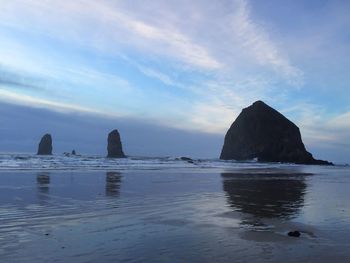 Rock formation on beach against sky during sunset
