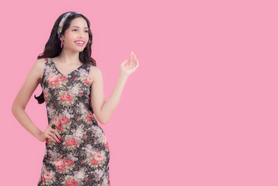 Portrait of a smiling young woman against pink background