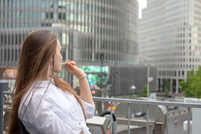 Side view of young woman by buildings in city