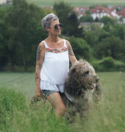 Woman with dog standing amidst grassy field