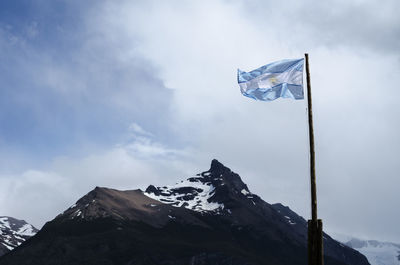 Low angle view of flag on snowcapped mountain against sky