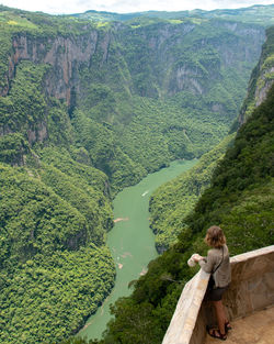 High angle view of woman standing in balcony over river by mountains