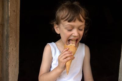 Portrait of smiling boy holding ice cream against black background