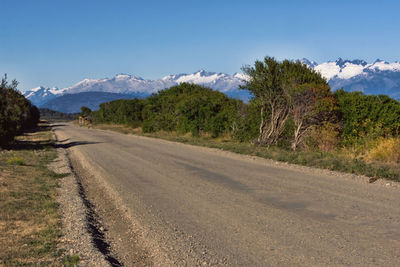 Dirt road by mountains against sky