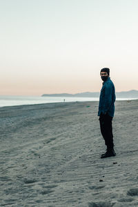 Man standing on beach against sky during sunset
