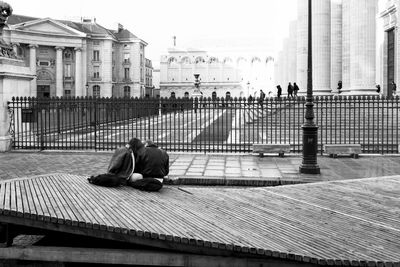 People sitting on street against buildings in city