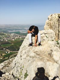 Man talking on mobile phone while sitting on cliff at mount arbel