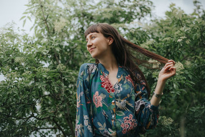 Young woman standing against plants