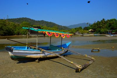 Boat moored on beach against clear sky