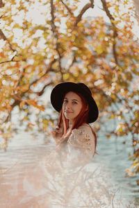 Portrait of a smiling young woman standing by tree